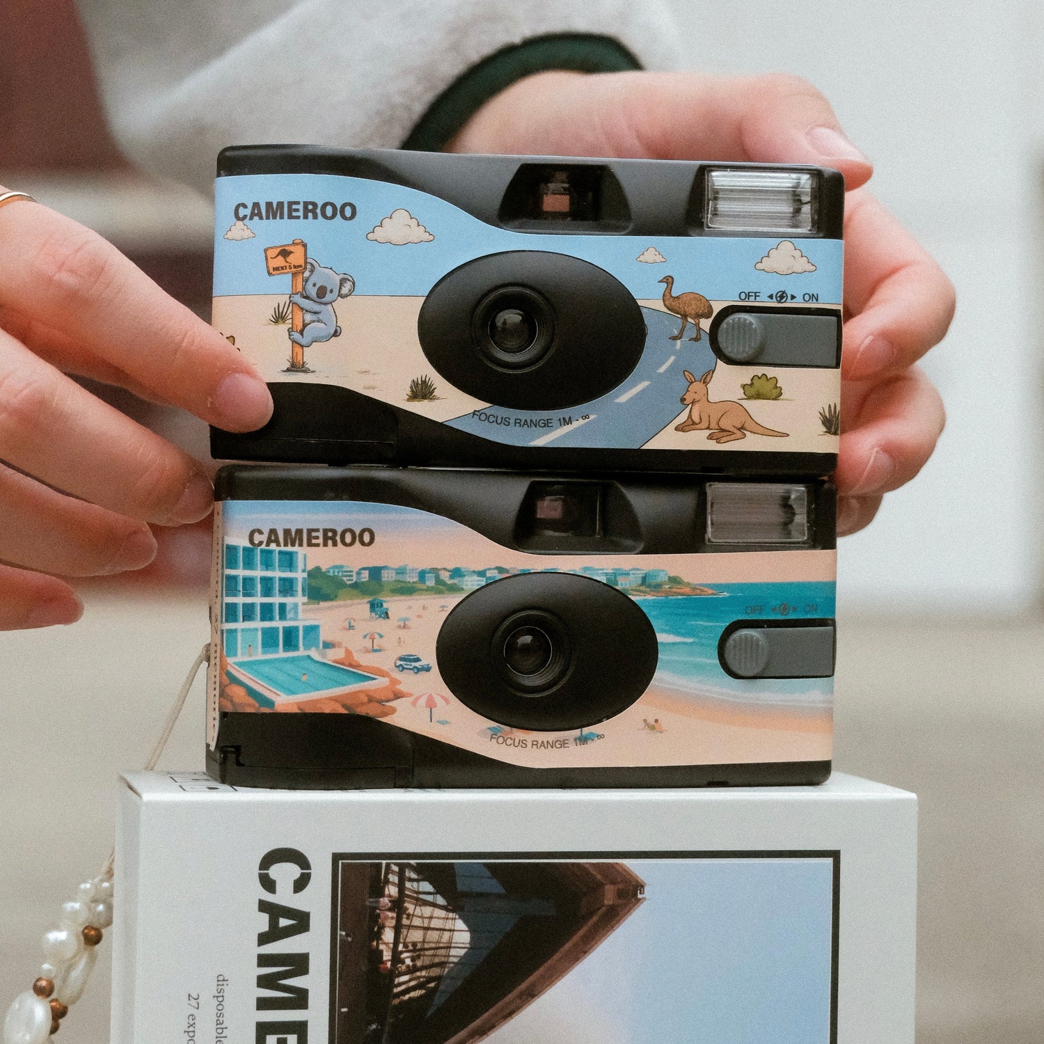 Cameroo disposable cameras with Australian illustrated designs stacked on product box